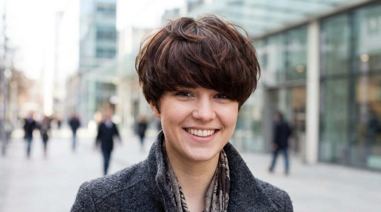 Portrait d'une jeune femme souriante avec une coupe boule volumineuse.