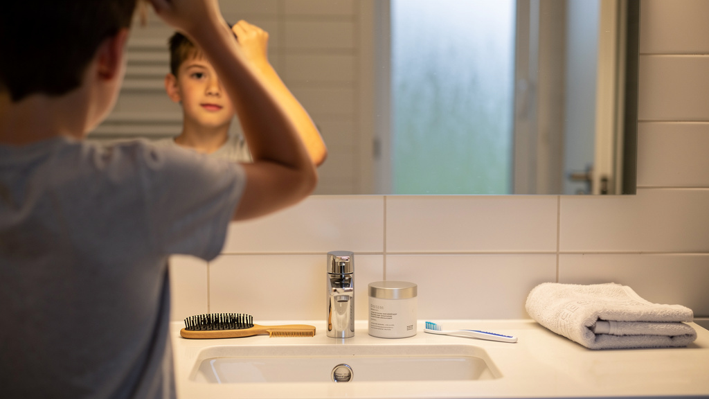 Ado garçon se coiffant devant un miroir de salle de bain