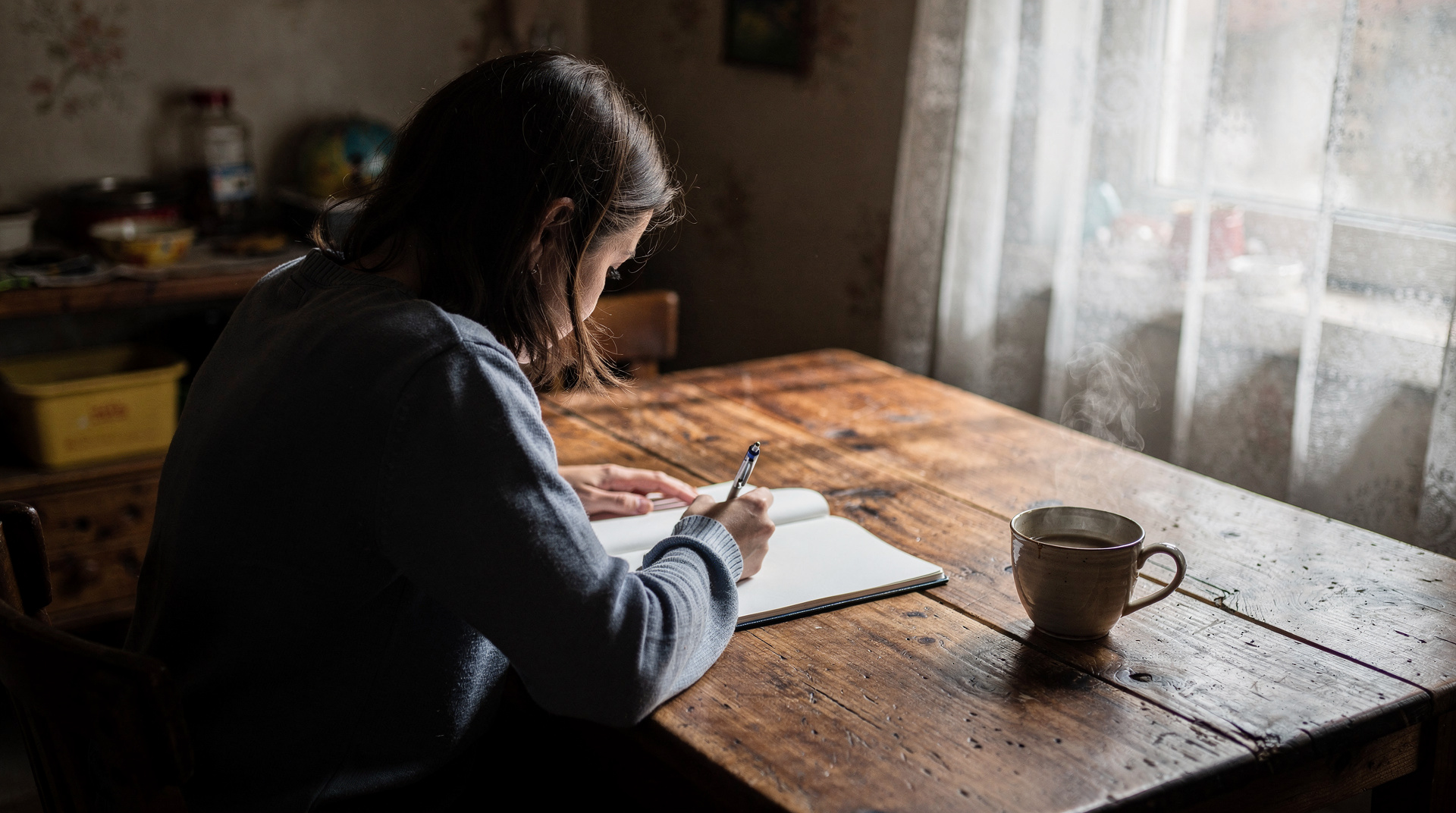 Personne écrivant dans un journal intime à une table en bois