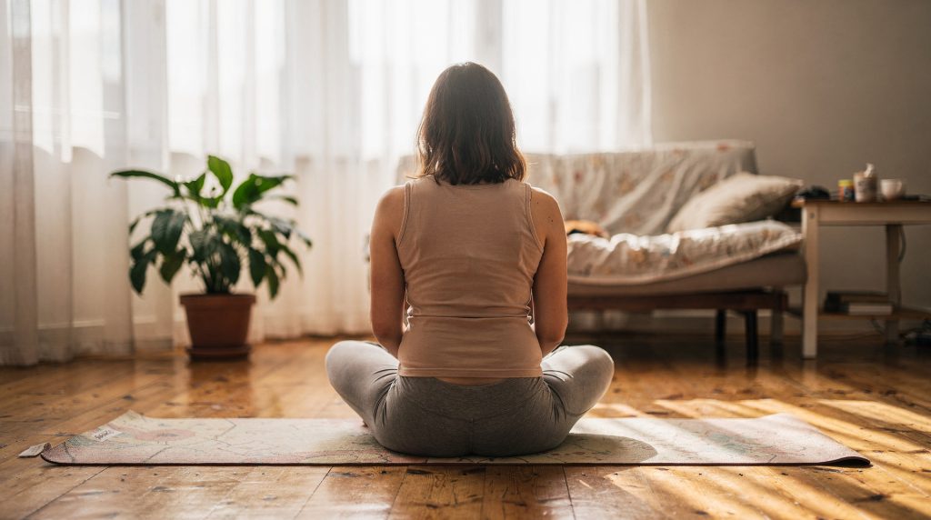 Femme enceinte en posture de yoga prénatal sur un tapis