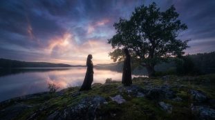Deux silhouettes sur une rive rocheuse, reliées par un lien doré lumineux, face à face devant un lac miroitant un ciel crépusculaire.