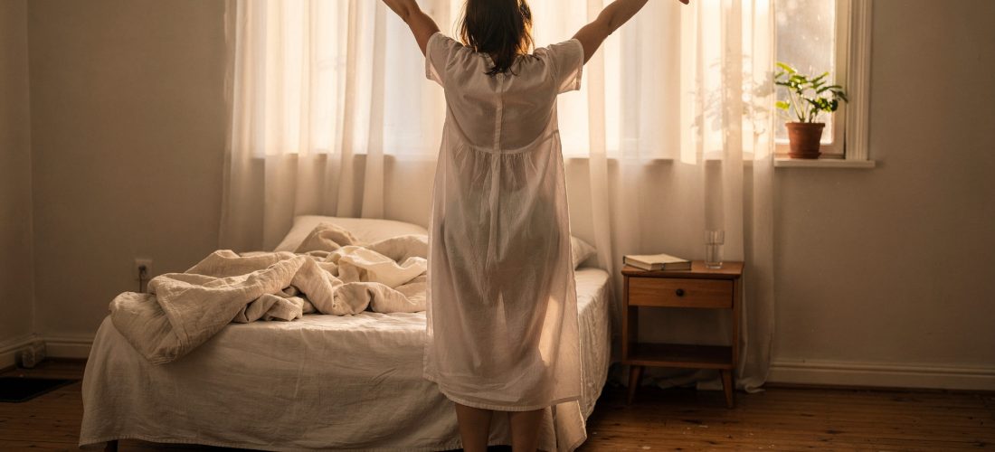 Femme qui s'étire au réveil dans une chambre lumineuse