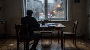 Homme pensif assis seul près d'une fenêtre le soir